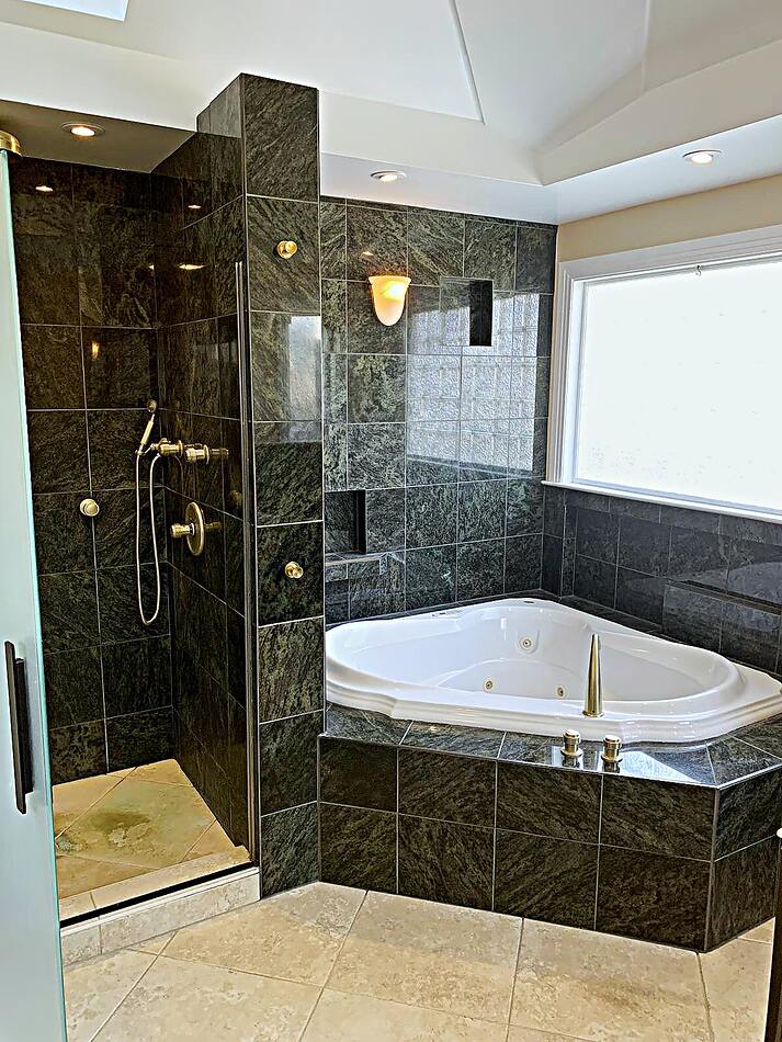 Green marble bathroom with corner tub and walk-in glass shower